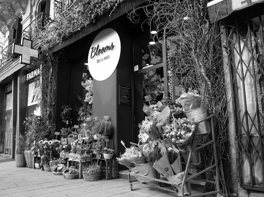 The storefront of Bloom's flowers & gifts, featuring a wide display of fresh flower arrangements and bouquets outside the shop. The floral displays include a variety of flowers such as roses, daisies,